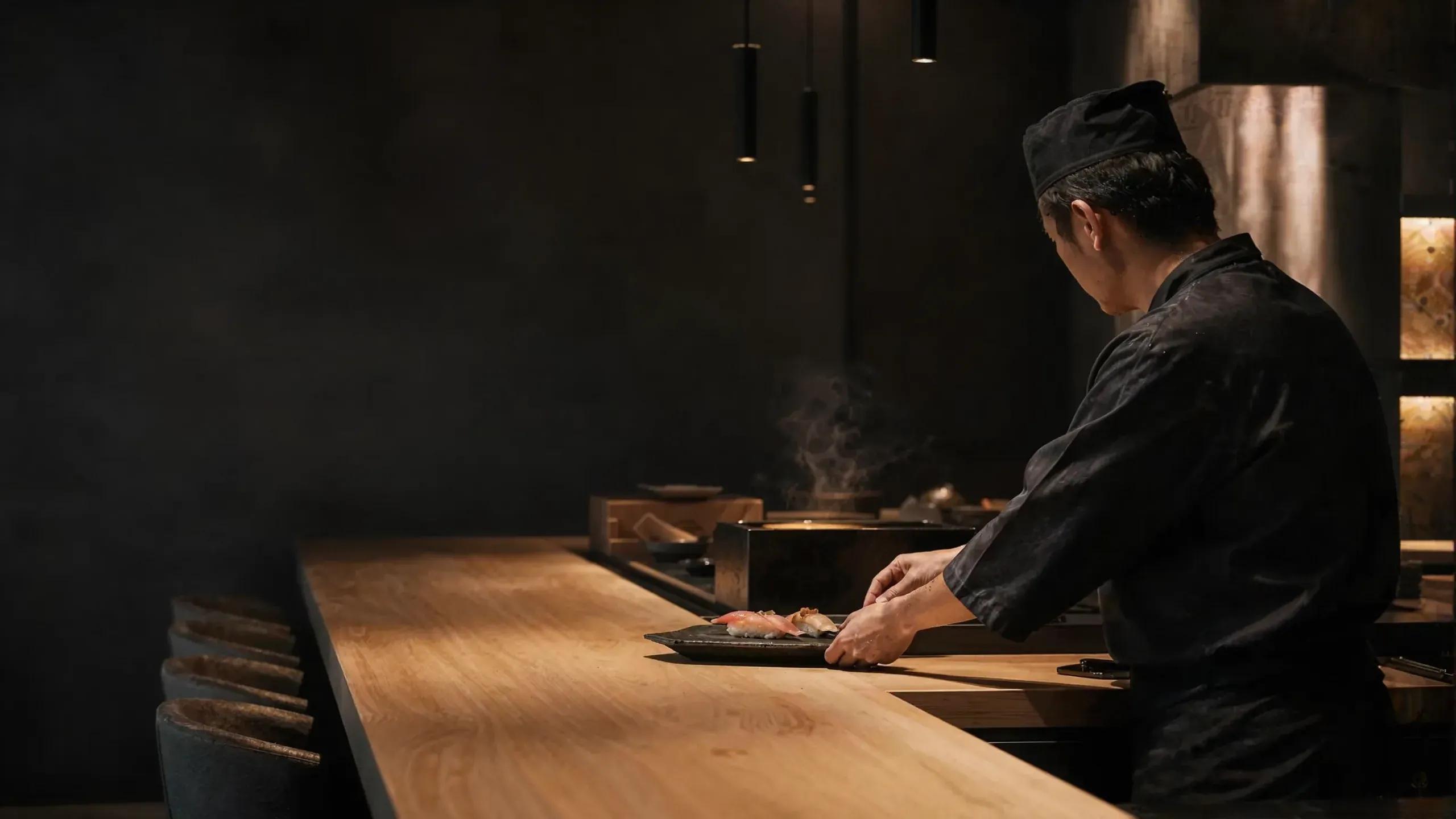 The chef at the hinoki counter, steam rising from the grill