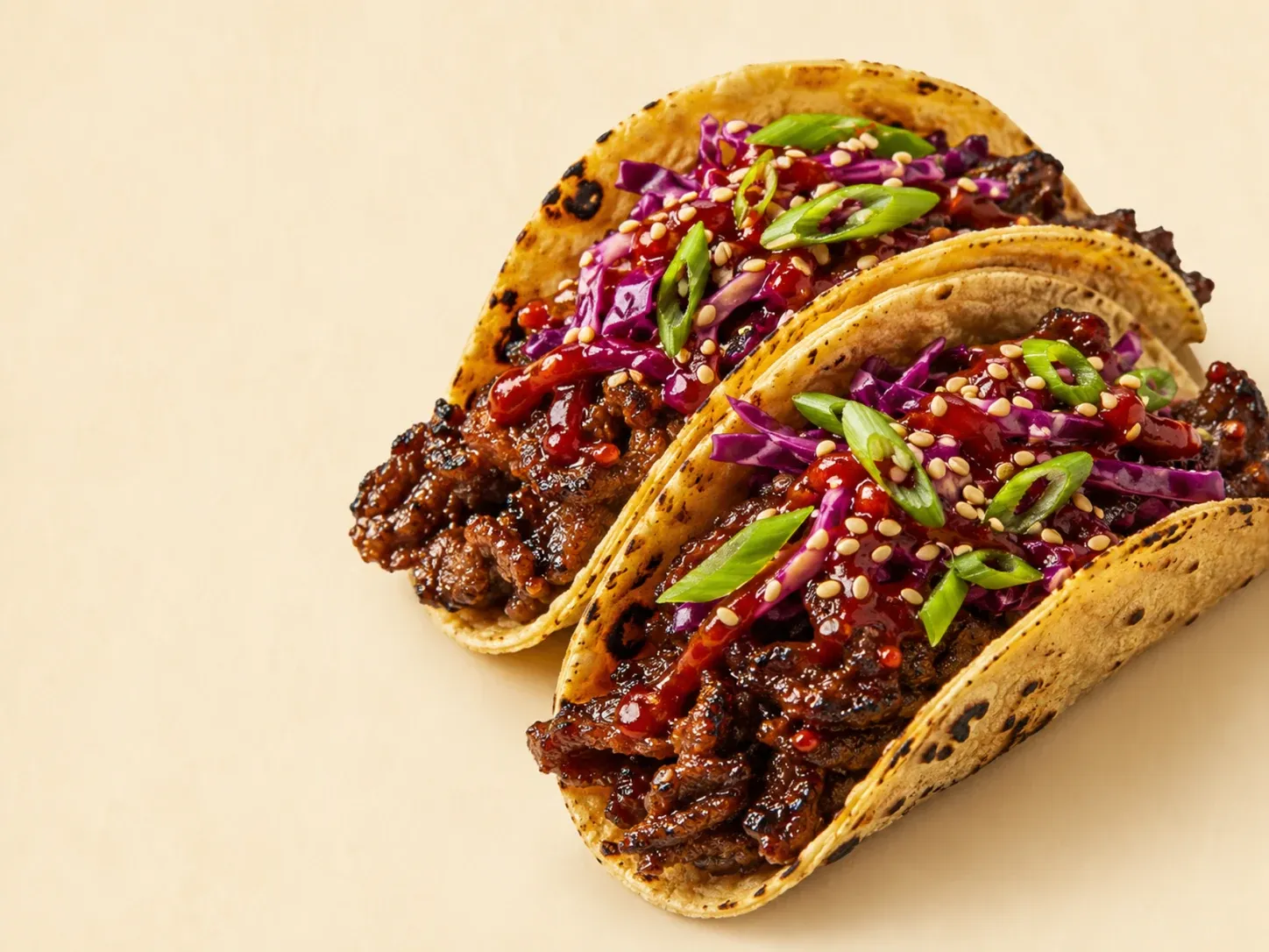 Two bulgogi tacos with purple slaw, scallions and sesame