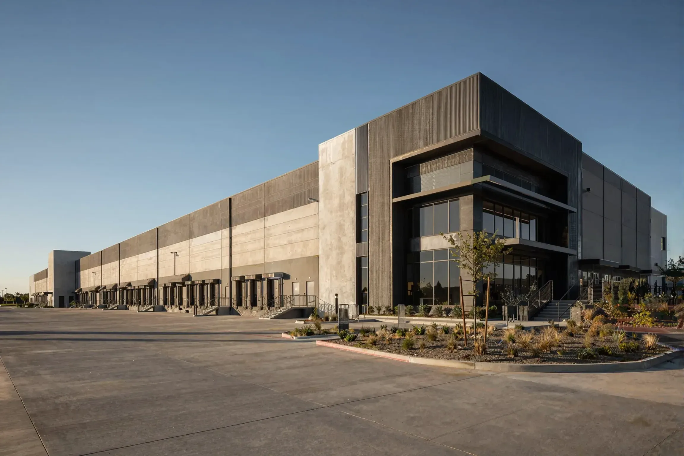 A concrete industrial building with loading docks under a clear sky