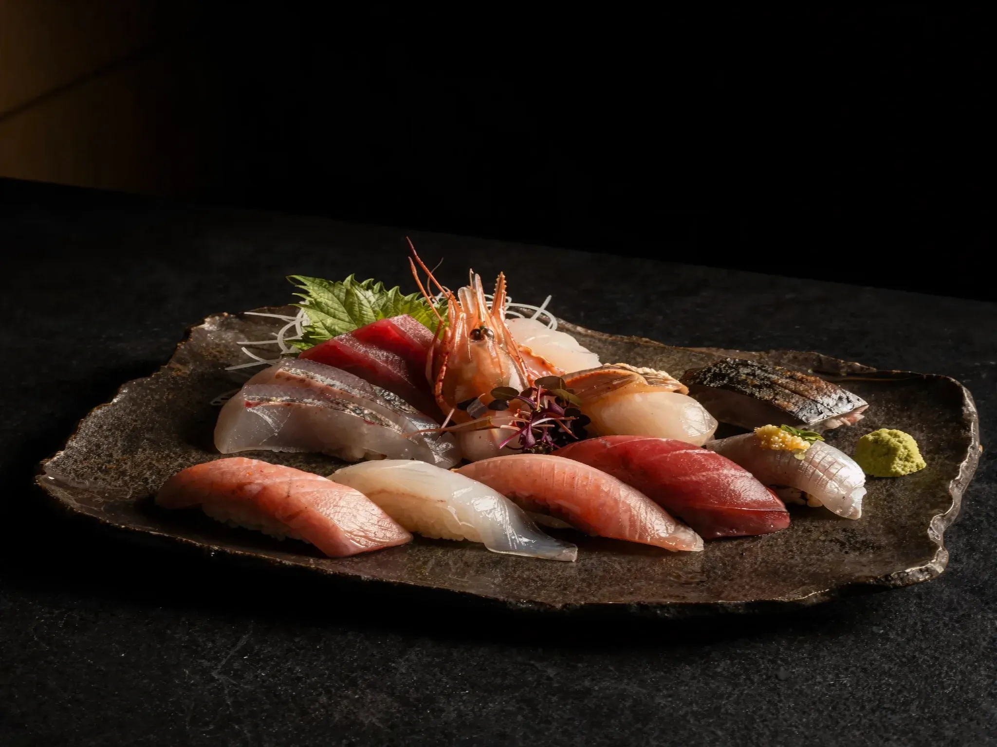 Nigiri of the season and sweet shrimp on a dark stone plate