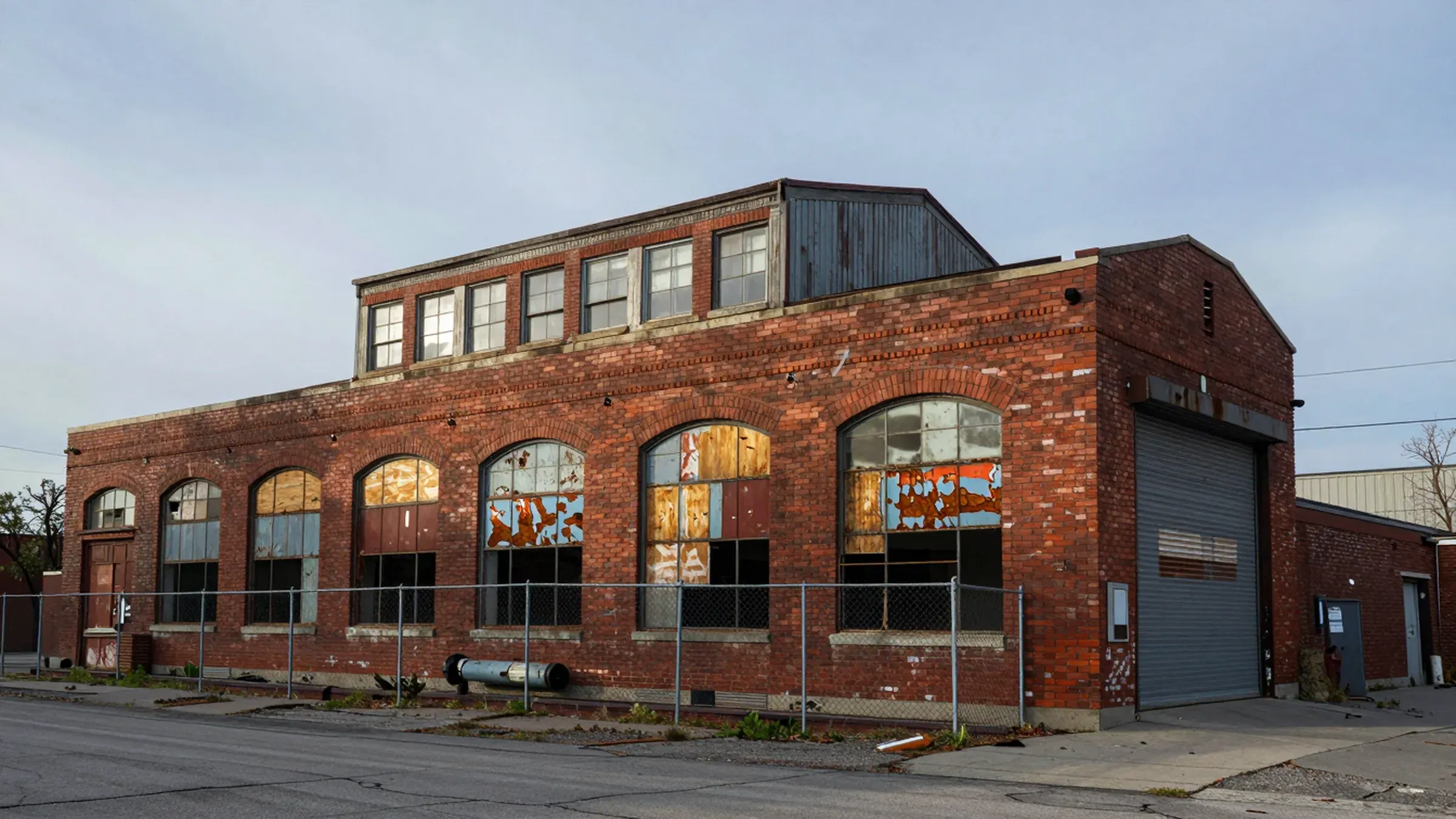 As found: the warehouse boarded up behind a chain link fence